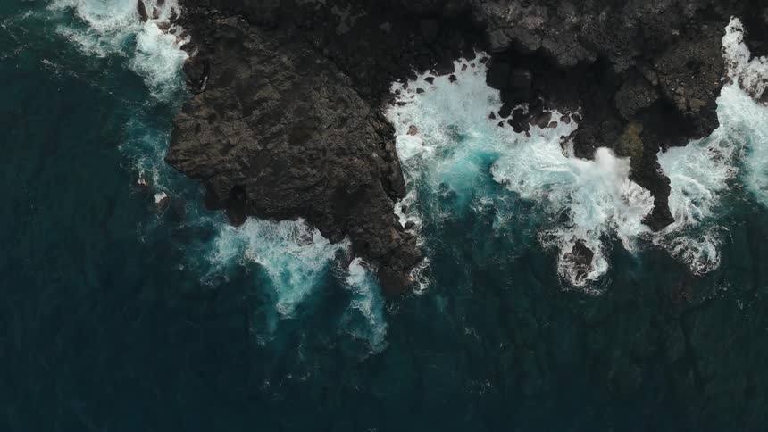 Aerial panorama of the turquoise blue sea with waves crashing on the coastal rock