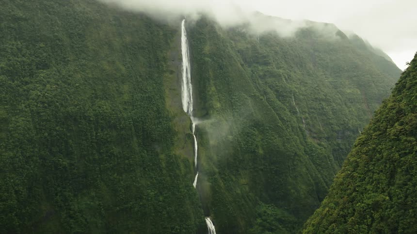 Aerial of a tall waterfall in a tropical mountain range