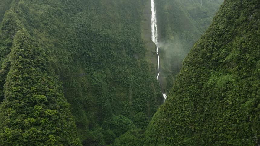 Hills with lots of green vegetation and a waterfall coming out of one of them