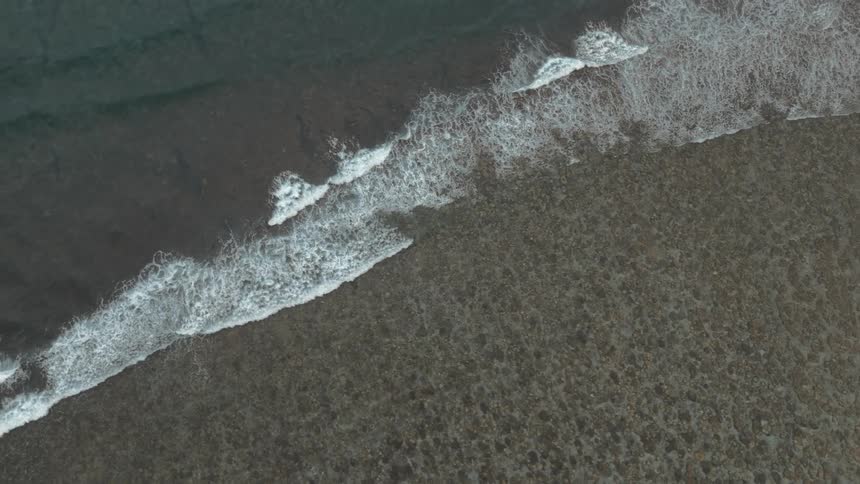 Aerial panorama of an extensive beach with sea waves contrasting with the land