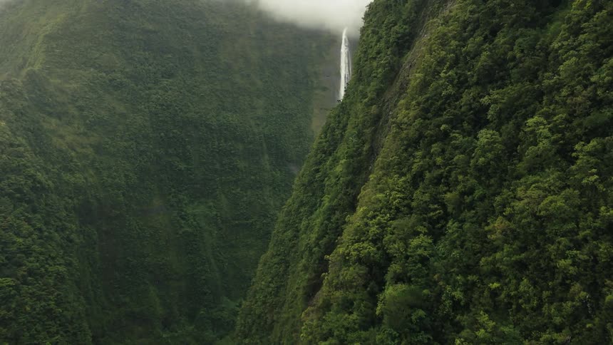 Aerial of a tall waterfall in a tropical mountain range