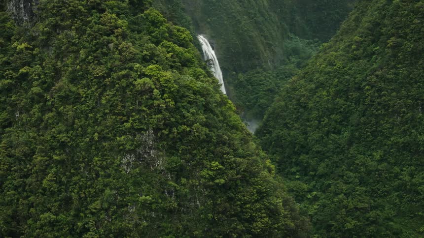 A waterfall drops water into a narrow mountain valley