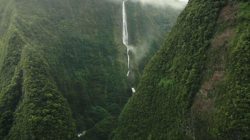 The cascade blanche waterfall flows through the canyon with vegetation and fog visible