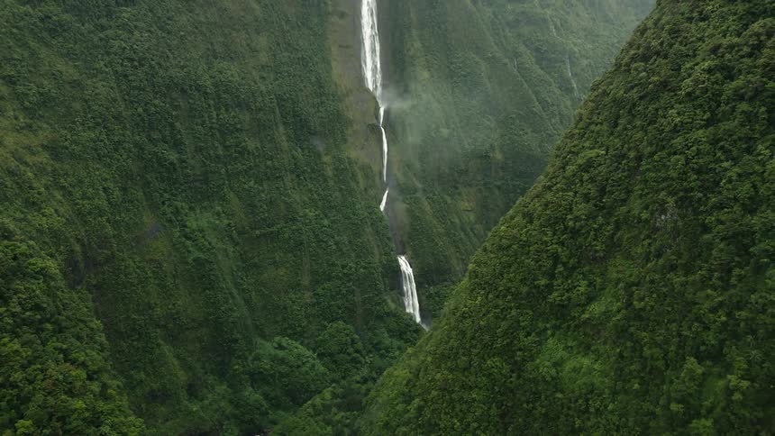 Aerial panorama of an extensive waterfall in green forested mountains
