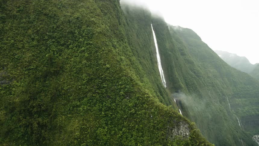 Landscape of forested mountain ranges with an extensive waterfall on a foggy day