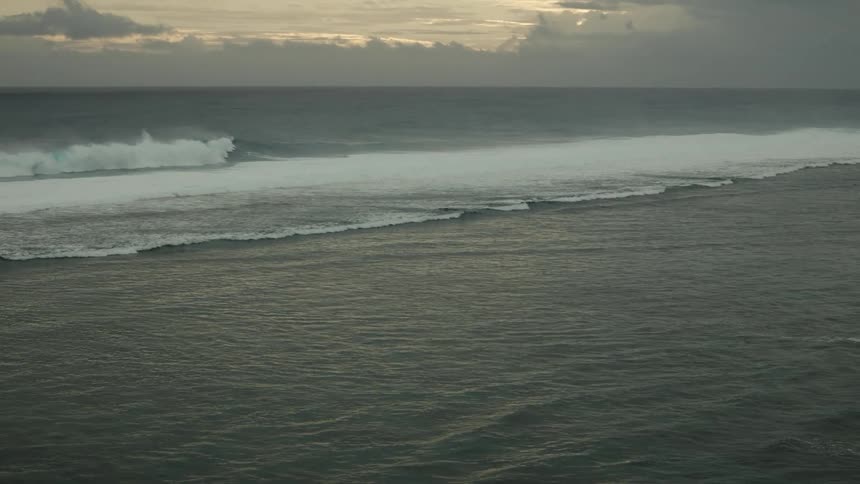 Landscape of an ocean with foamy waves on a cloudy day at dawn