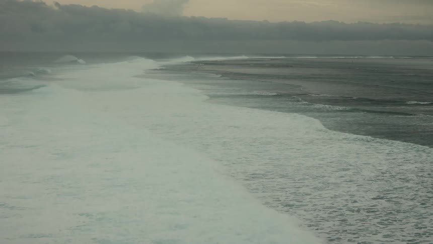 Aerial landscape of a vast sea with long foaming waves and a morning sky