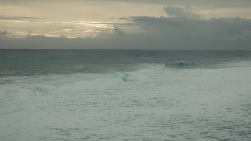 Shallow waves roll in toward the beach as the sun rises