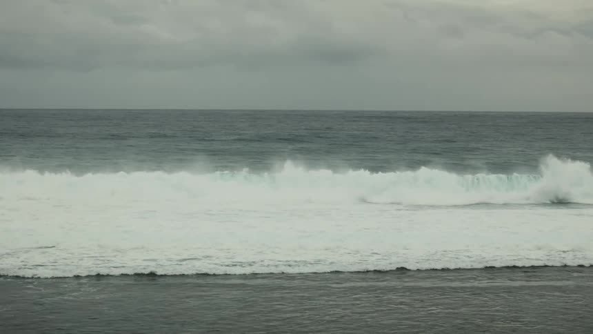 Landscape of a wave breaking in the middle of the sea and forming foam on a cloudy morning