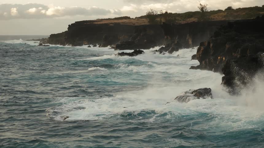 Landscape of strong sea waves hitting coastal rocks in the late afternoon