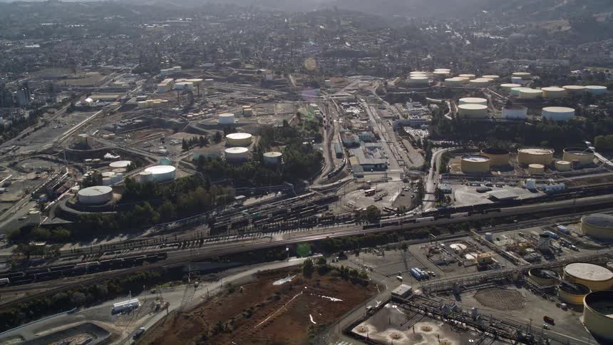 Aerial panorama of factories and power plant in an urban city with hills and mountains around the horizon