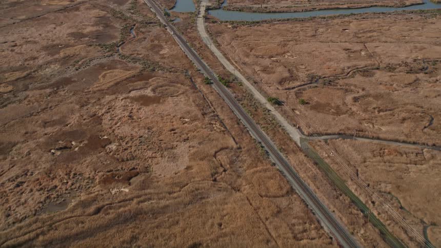 An aerial view of a large desert asphalt route that passes over a small river