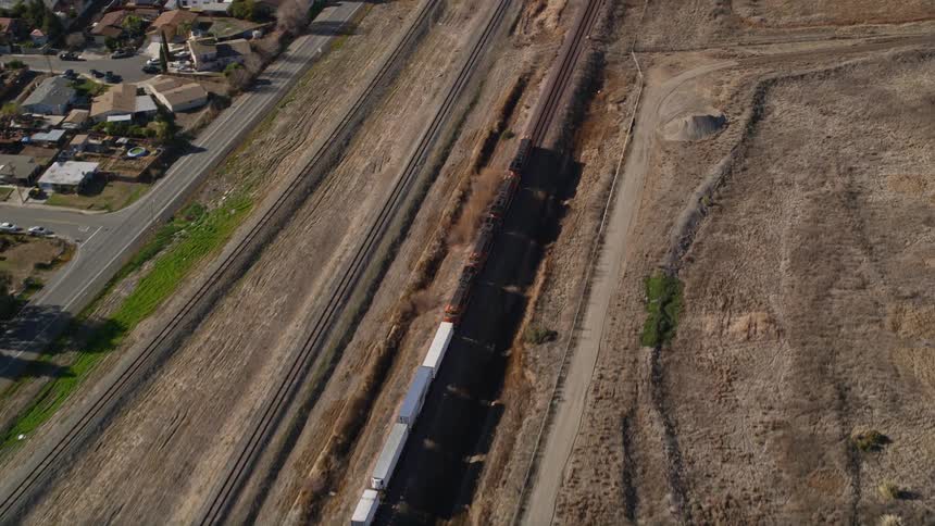 A train moves down tracks next to a suburb