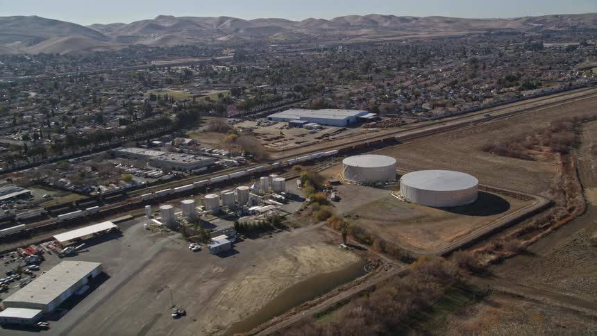 Aerial panorama of a freight train passing near an urban city with mountains on the horizon