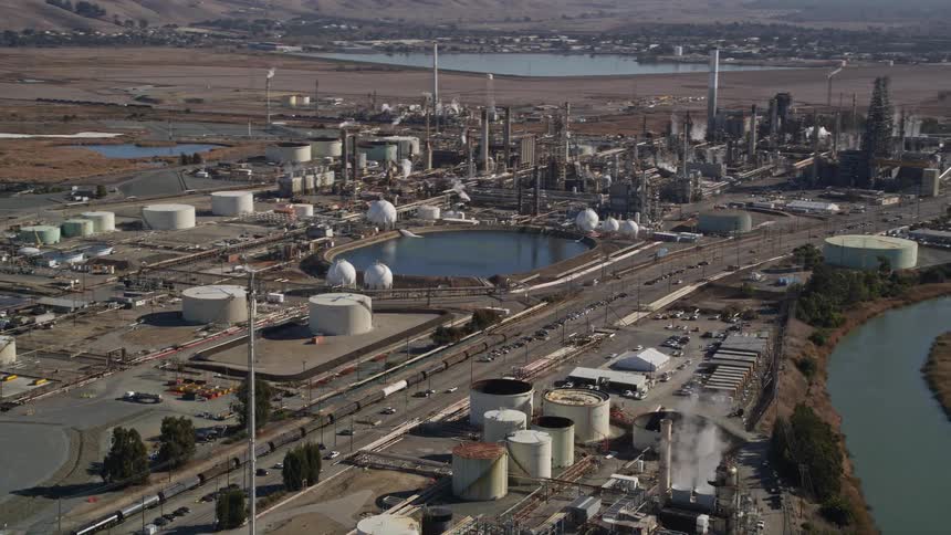 Aerial panorama of lakeside power plants in a natural setting with an urban city on the horizon and hills