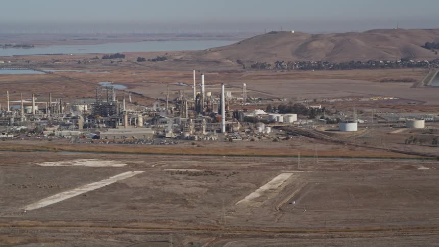 Aerial panorama of a power plant in a natural location with hills and the sea on the horizon