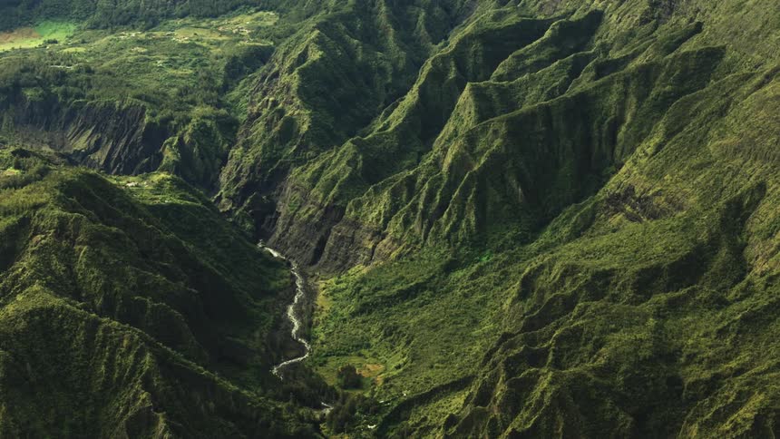 A small stream runs through the green mountains
