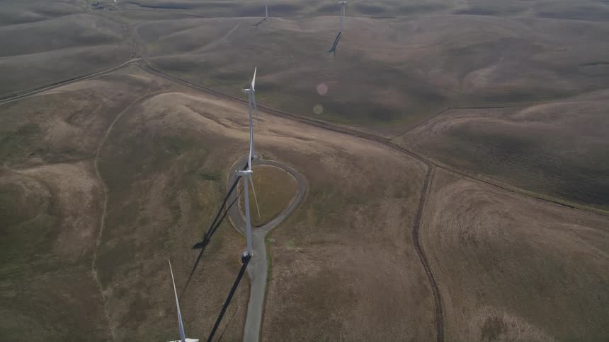 Aerial panorama of wind energy engines on hills and natural fields during daytime