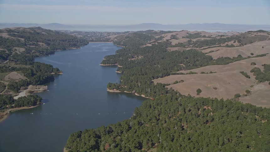 A river and rural area near rolling hills and forests and mountains