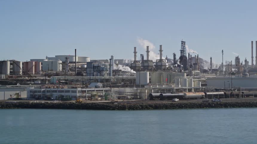 Industrial refinery with several structures and chimneys on the edge of a maritime canal