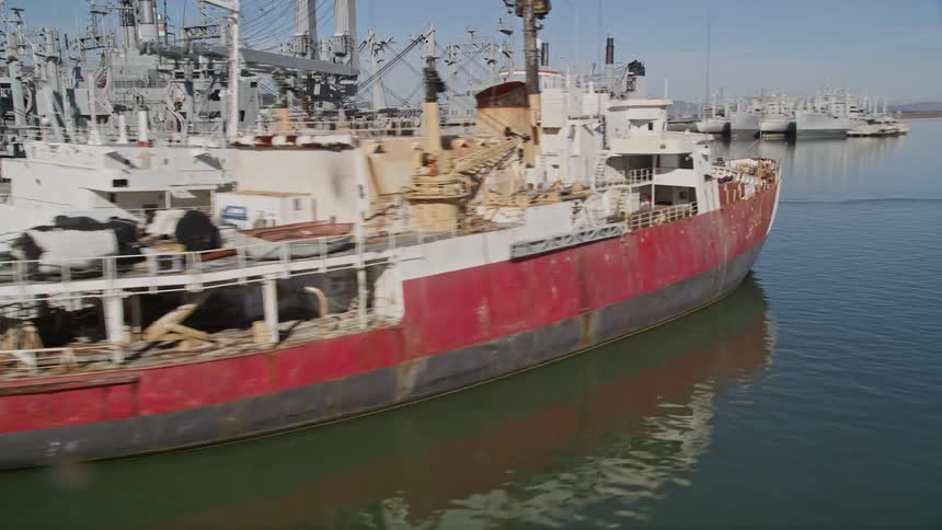 A fleet of similar ships is parked on a pier in the middle of a bay