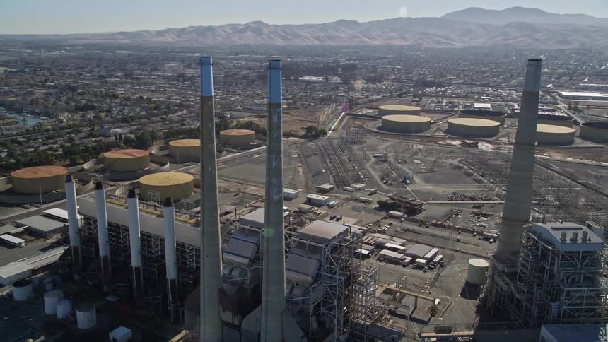 Panorama of a hydroelectric plant with large chimneys by the sea and an urban city