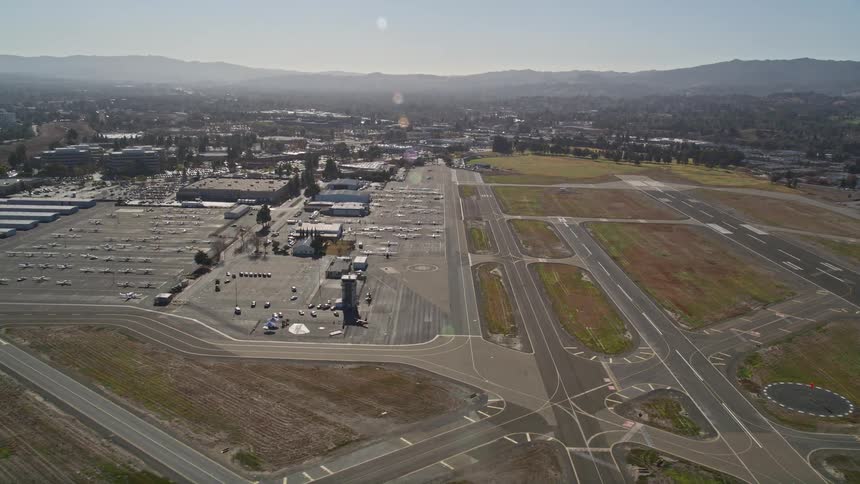Aerial scene of the runways of an airport located in the middle of an urban city with mountains around on a clear blue sky day