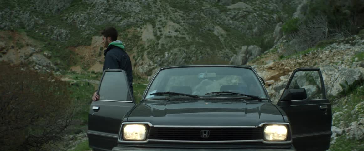 Two people in a car coming to a stop on a mountain road