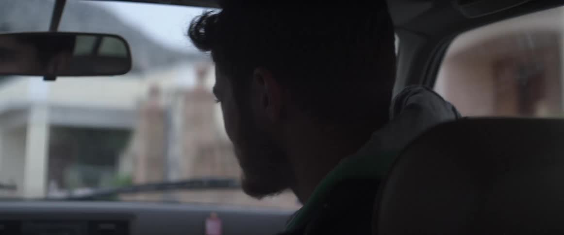 A man with a beard sitting passenger seat in a moving car