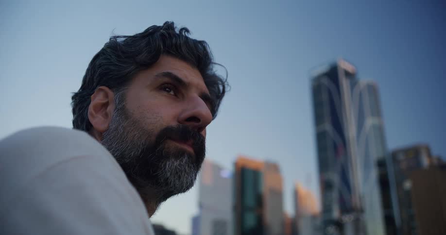 Bearded man looks around with skyscrapers in the background
