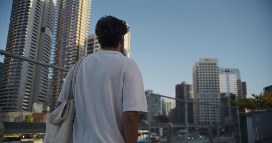 A man walks near a fence in a city