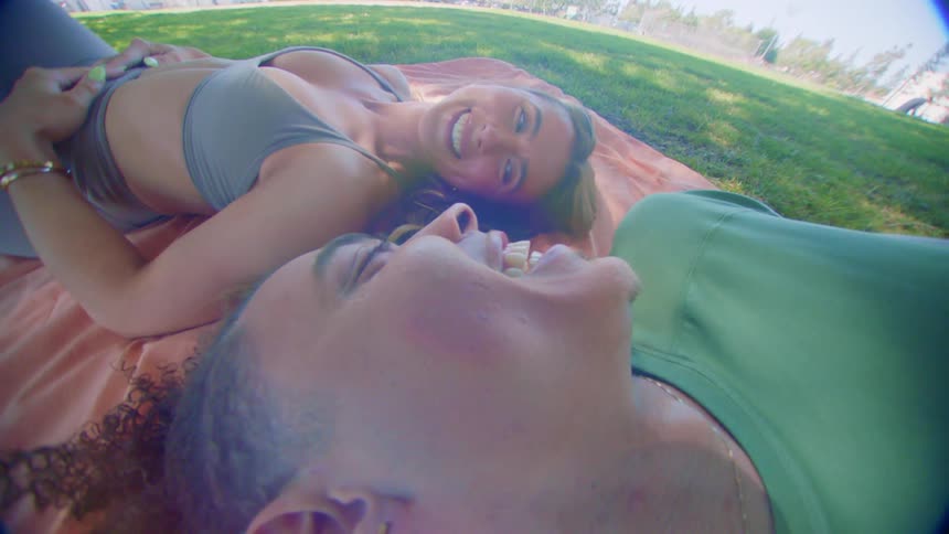 A young couple of friends laugh and smile in the park