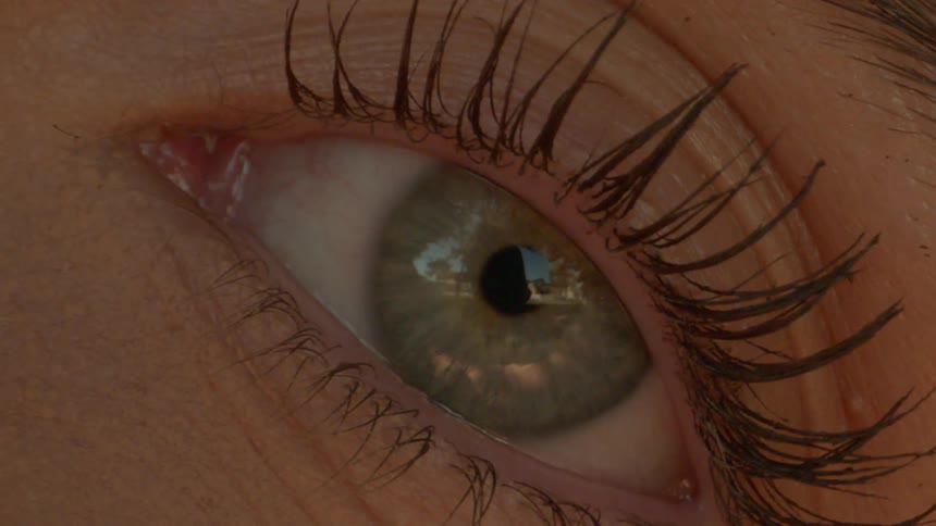 A persons eye with a green iris and it is blinking