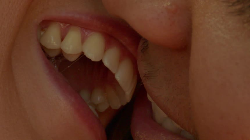 Extreme closeup of a man and womans mouth kissing romantically and smiling