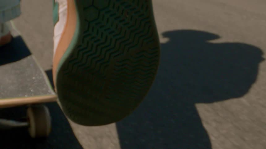 Feet of a person riding a skateboard on the asphalt