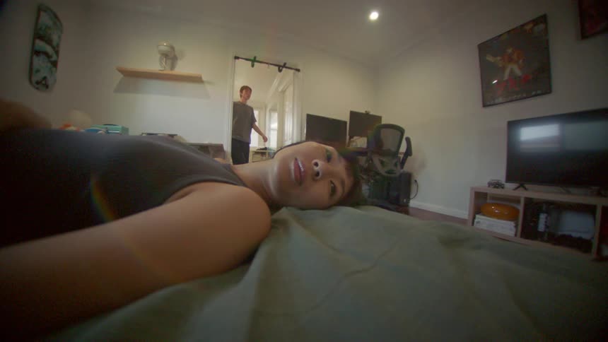 A woman lying in bed and a man entering the room and the sun shining through the window