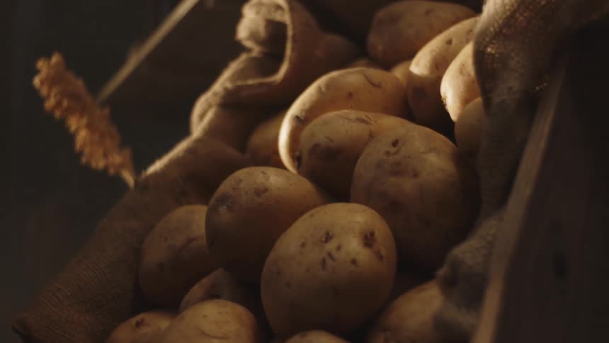 A man sets down a box full of potatoes