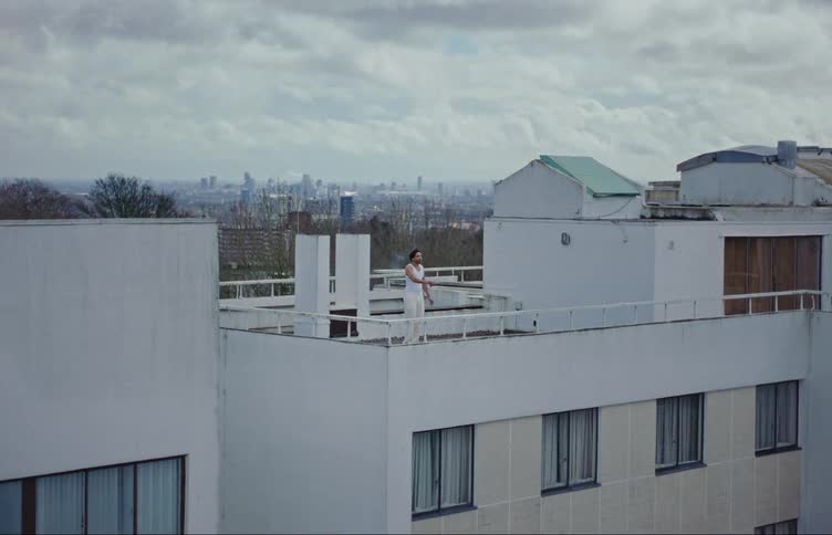 A man stands on the roof of a building while smoking