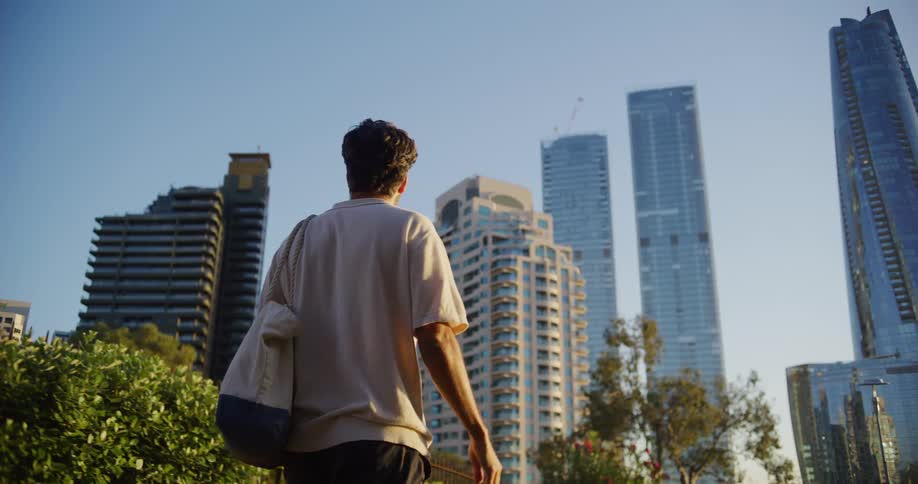 A man with a bag walks and looks at a city