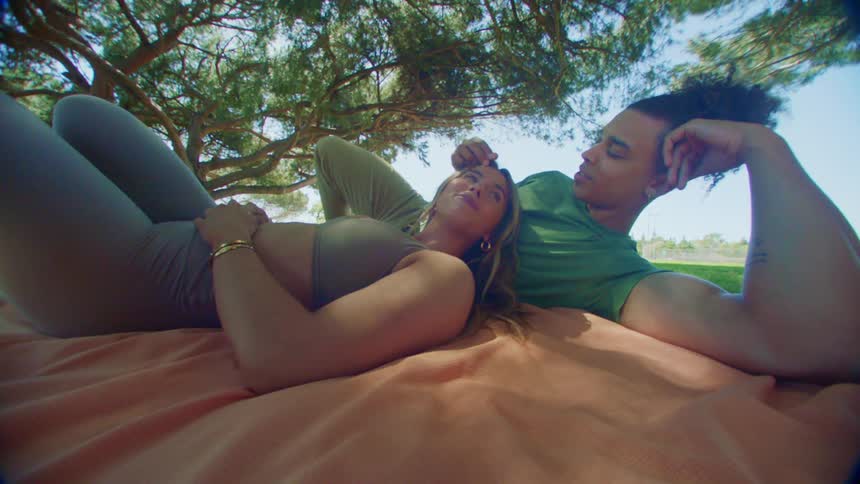 A man and woman lie on a blanket enjoying each others company