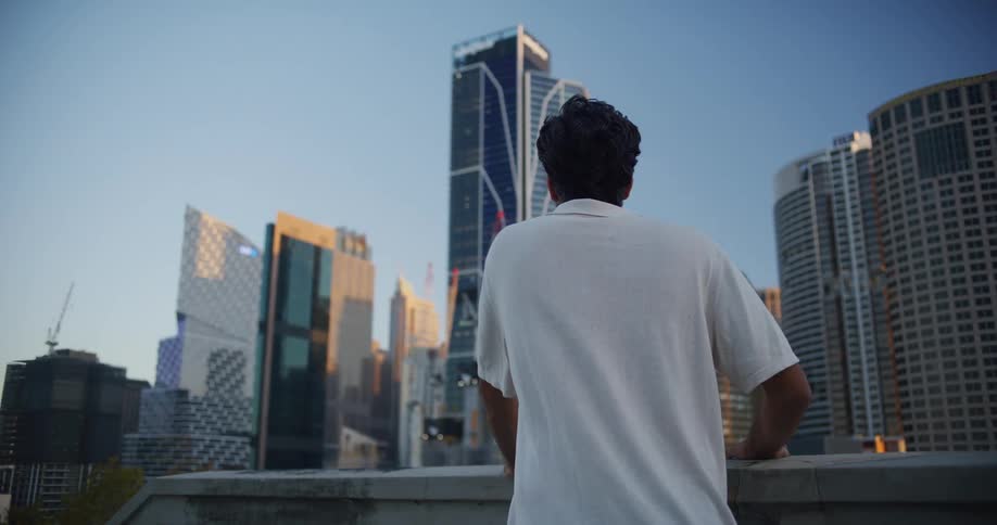 A man in a casual collared shirt stands before a city skyline