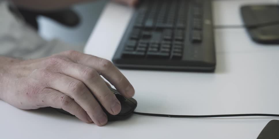 A man scrolls on a mouse in an office