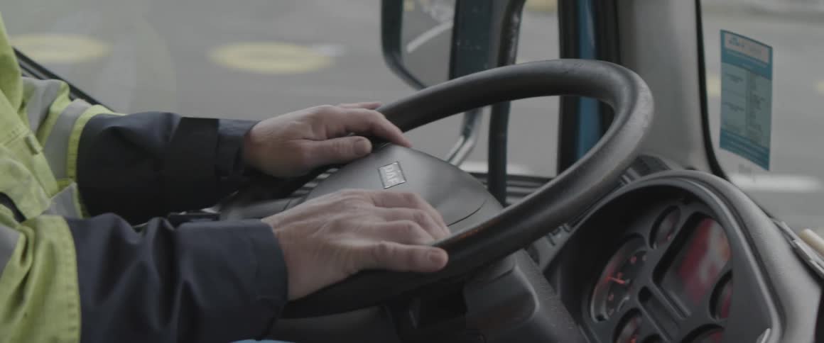 A closeup of a persons hands on a steering wheel inside a vehicle