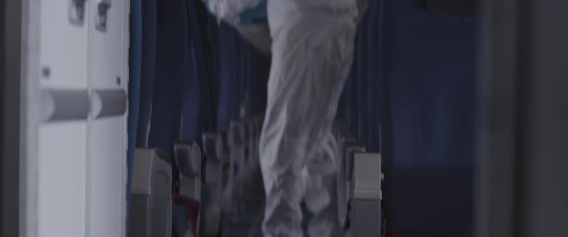 A person in a protective suit is inside an aircraft cabin