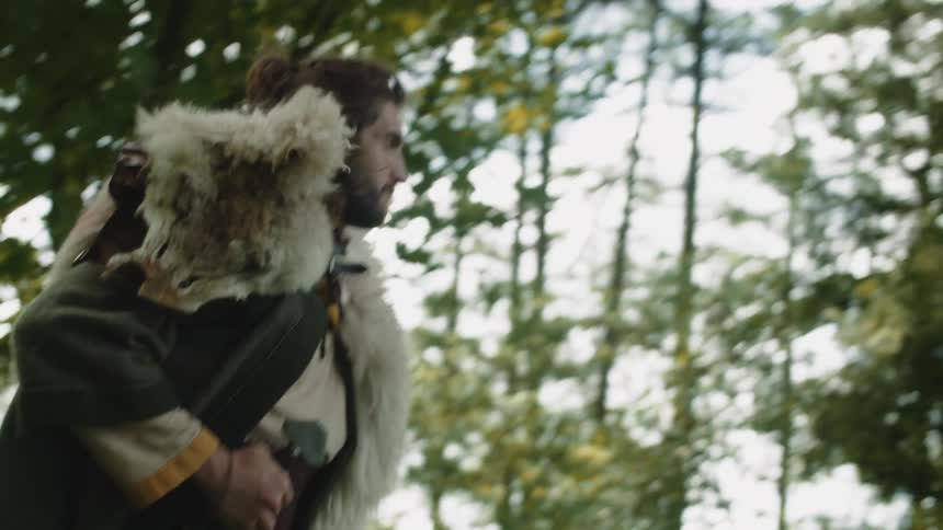 Man walking in the forest holding his sword at his waist