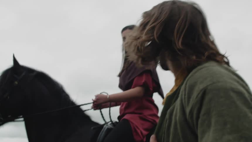 Man walking on foot next to a woman riding a horse