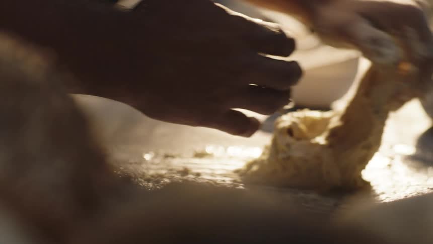 A man kneads dough on a wet table