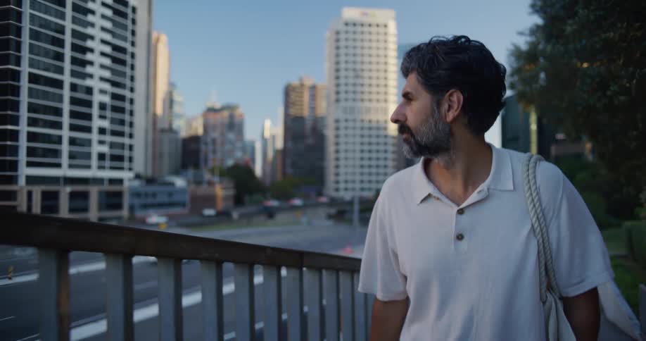 Man walking and looking at an urban landscape with tall buildings