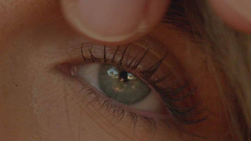 A person brushes hair away from a womans eye