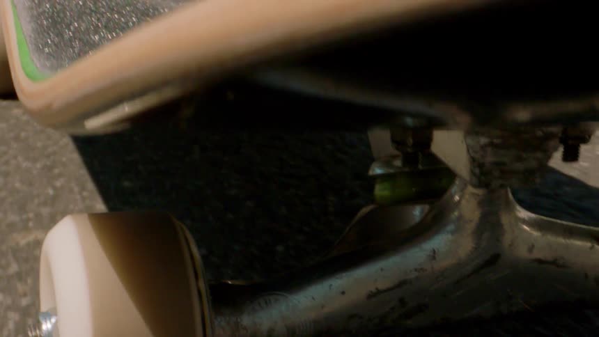 Closeup on a skateboard with a person riding on an asphalt